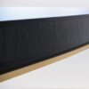 A contemporary dining table in a sycamore black with a shadow gap and brushed brass trim detail to the frieze.
