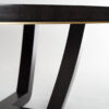 A contemporary dining table in a sycamore black with a shadow gap and brushed brass trim detail to the frieze.
