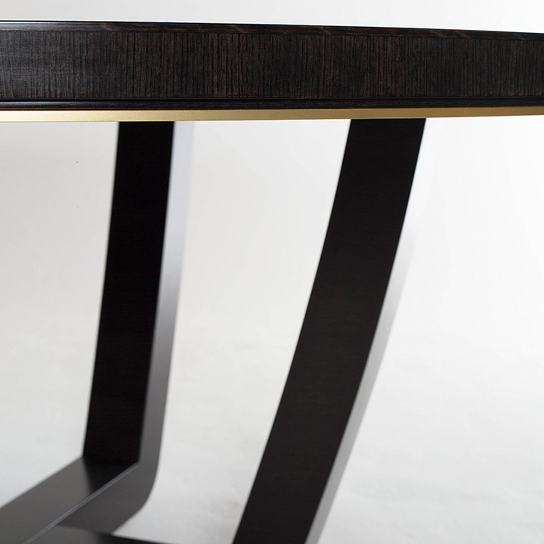 A contemporary dining table in a sycamore black with a shadow gap and brushed brass trim detail to the frieze.