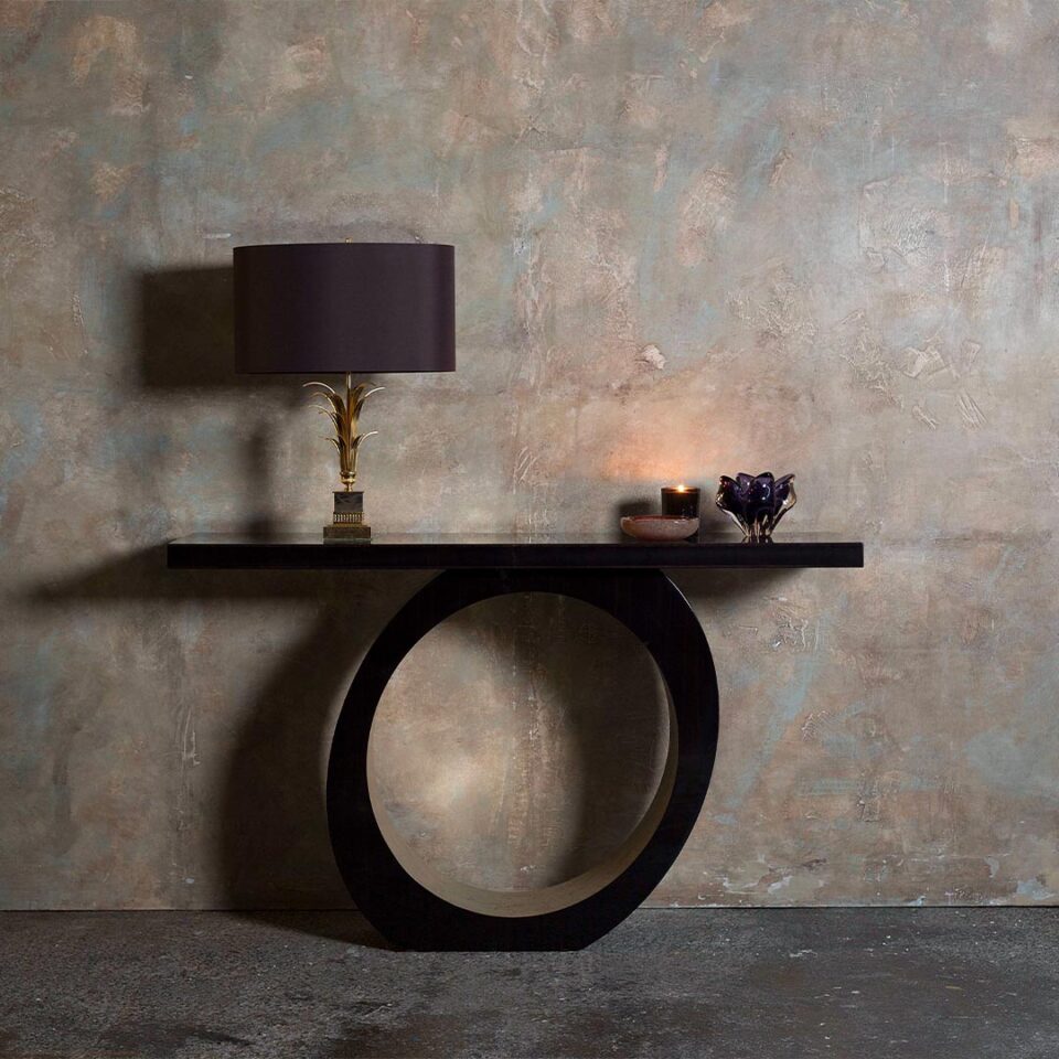 A contemporary console table with an edgy, asymmetric slant. Finished in a dark tinted Macassar ebony with the inside pedestal hand gilded in a distressed white gold leaf.