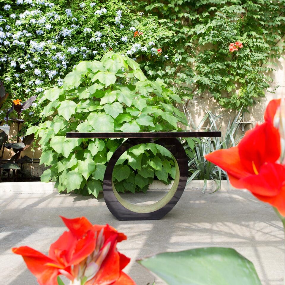 A contemporary console table with an edgy, asymmetric slant. Finished in a dark tinted Macassar ebony with the inside pedestal hand gilded in a distressed white gold leaf.