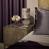 A sleek bedside chest in a glossy sycamore dusk with a glamorous  brushed brass plinth and trim