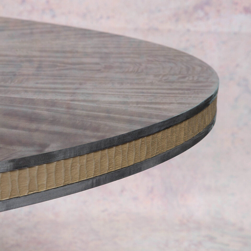 A detail frieze image of this glamorous dining table finished in a pebble grey anegre with a hand carved liquid bronze relief trim