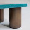A glamorous coffee table finished in a stylish blue birdseye maple with four cylindrical antique brushed brass legs