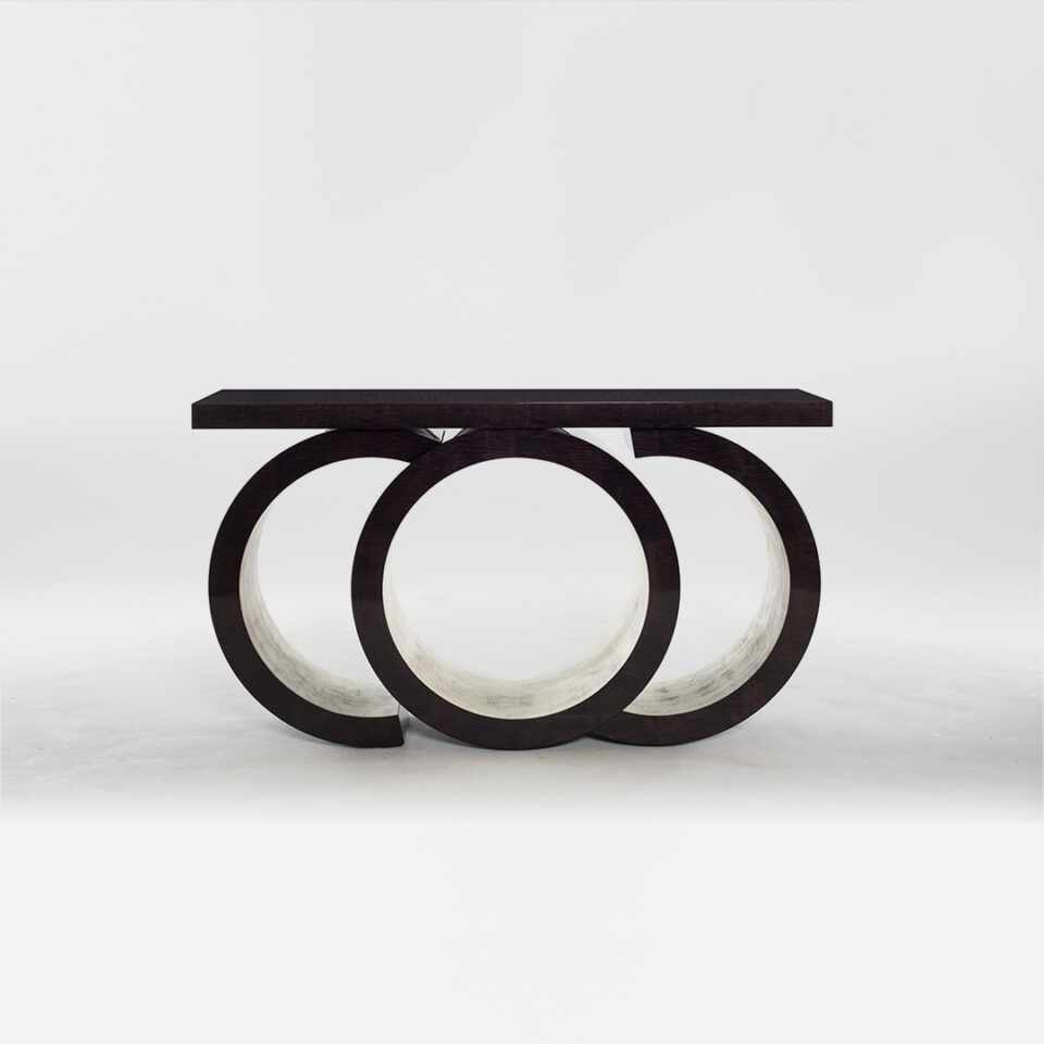 A statement console table with a sculptural silhouette. Finished in in a high gloss sycamore black with glamorous moon gold leaf gilding to the inner pedestal. Design by DAVIDSON London.