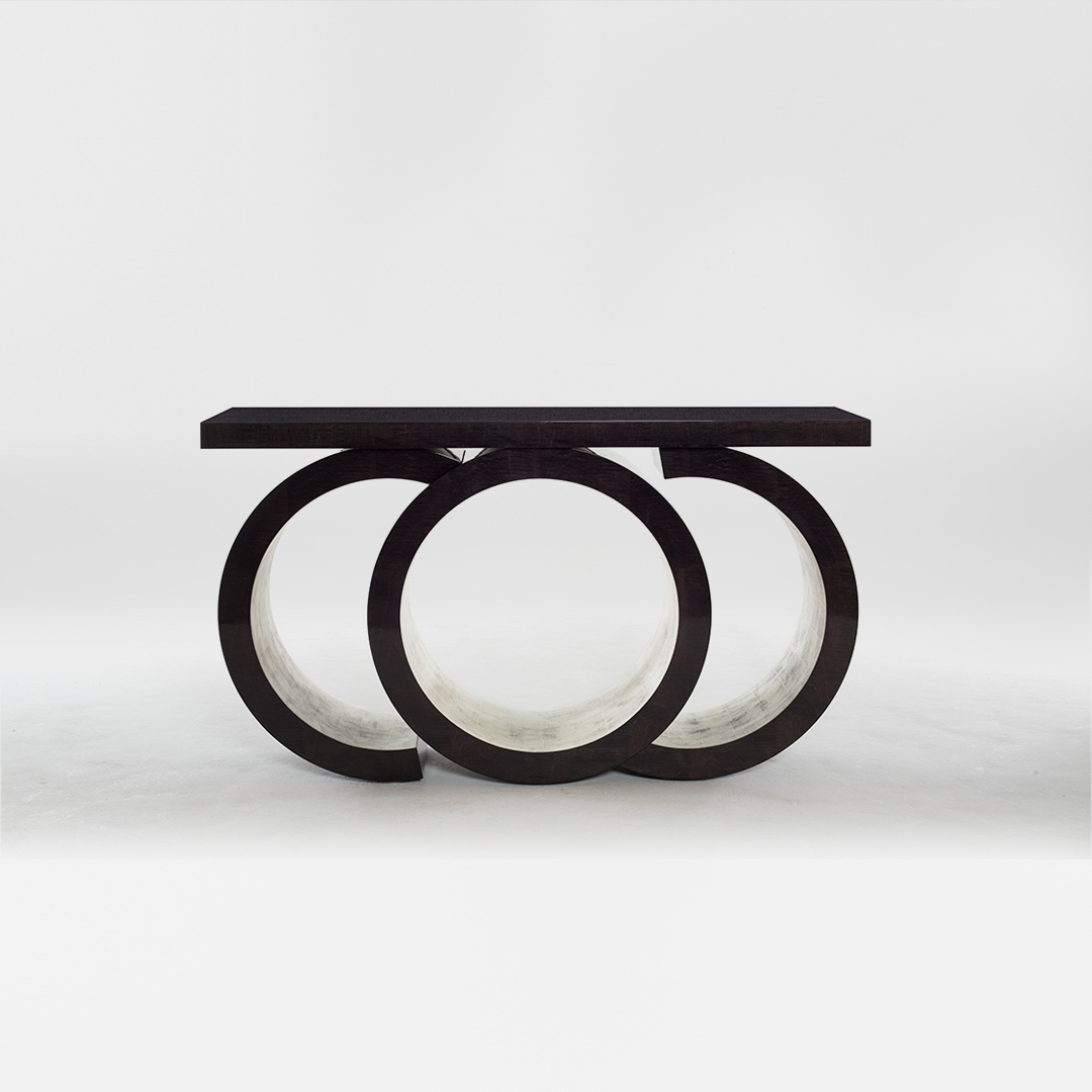 A statement console table with a sculptural silhouette. Finished in in a high gloss sycamore black with glamorous moon gold leaf gilding to the inner pedestal. Design by DAVIDSON London.