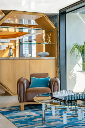A seating area with a large leather armchair and a round games table in a luxury Bangkok penthouse.