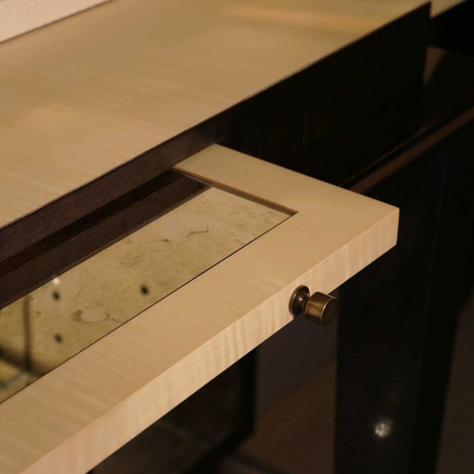 A stylish 2 door drinks cabinet with high gloss sycamore black legs and hand carved liquid bronze doors. Design by DAVIDSONLondon.