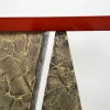 a console table with a distressed bronze base and a red high gloss lacquer top