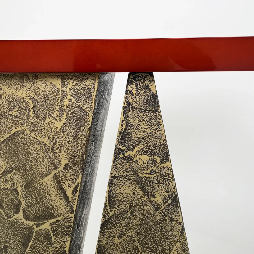 a console table with a distressed bronze base and a red high gloss lacquer top