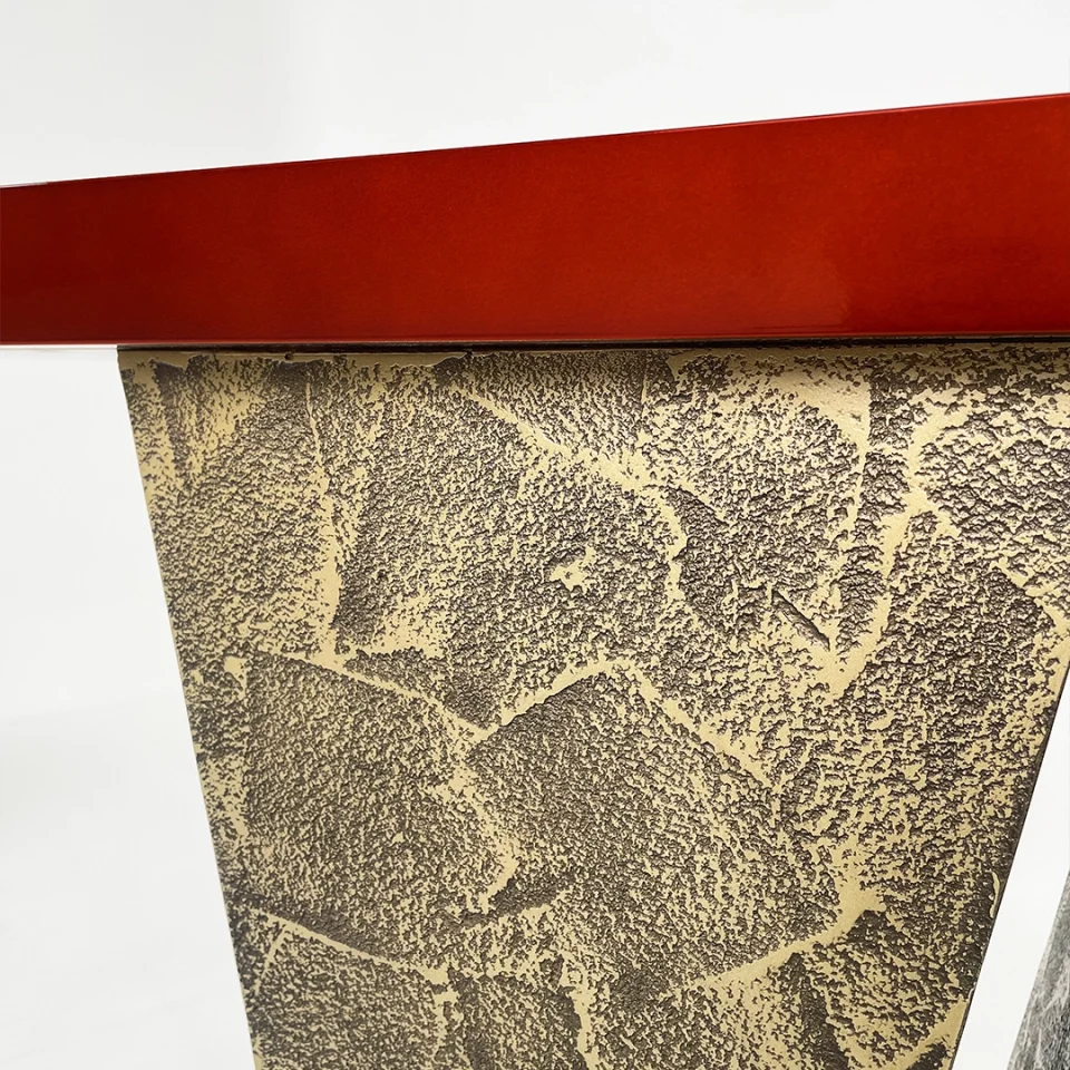 a console table with a distressed bronze base and a red high gloss lacquer top