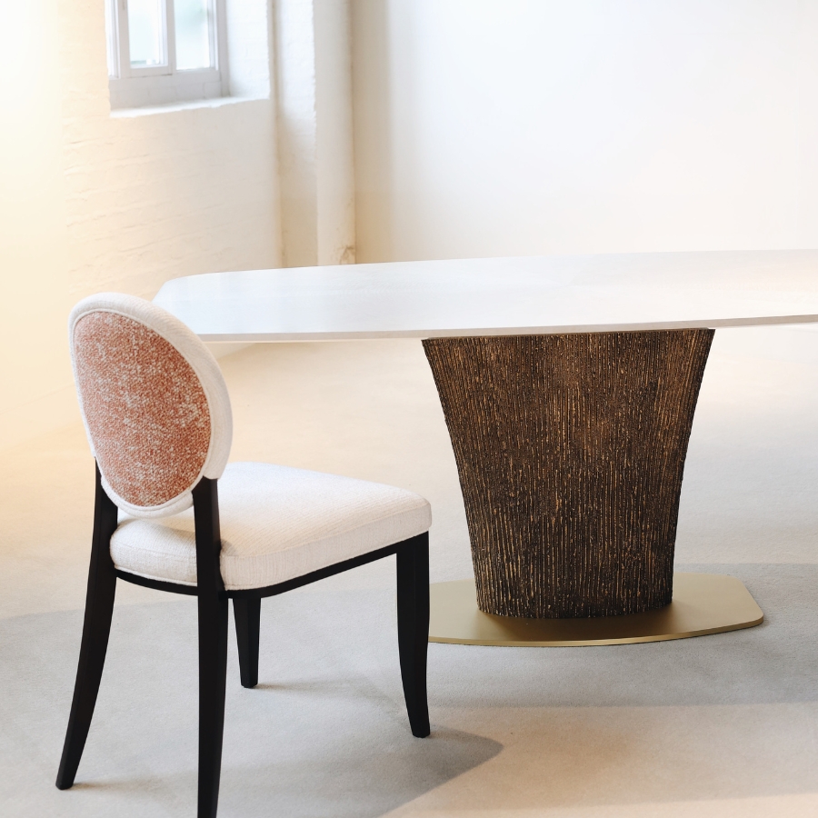 corner view of the Magdon luxury bronze dining table on a light grey with a Winslet Chair win white and orange fabric