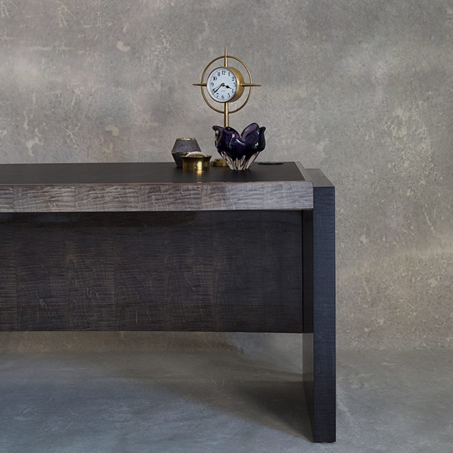 A writing desk with a sleek modesty panel finished in a two tone sycamore grey and sycamore black with a smart leather writing surface